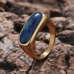 Detailed close-up of a gold ring with oval blue lapis lazuli stone on dark bark texture