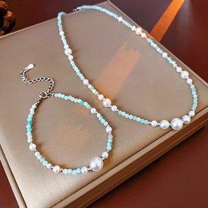 Gros plan sur ensemble collier et bracelet en perles factices avec petites perles bleues