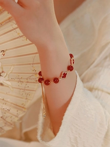 Detail of red agate beads and golden clover charm on adjustable retro style bracelet