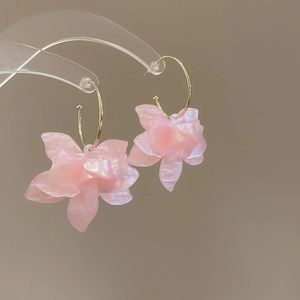 Détail d'une boucle d'oreille fleur en résine rose avec crochet doré sur support