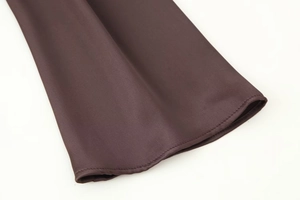 Detailed close-up of dark brown satin fabric texture and premium double stitching on dress