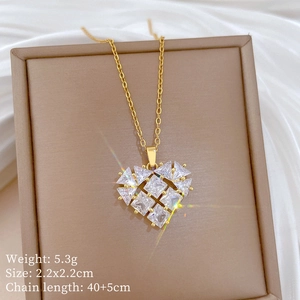 Detail of gold heart pendant with cubic zirconia stones on a beige display stand