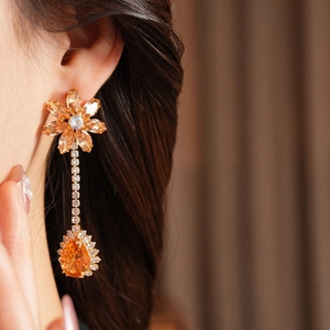 Detail of luxury drop earrings with orange flower zircon and water drop stone