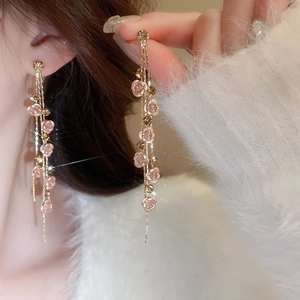 Detail of elegant long tassel earrings with pink flocking roses and gold chains on model