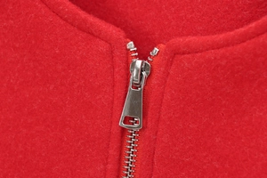 Macro view of silver metal zipper closure on a soft red wool-textured pilot jacket