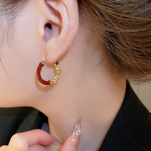 Détail de la boucle d'oreille géométrique en émail rouge et or sur un mannequin