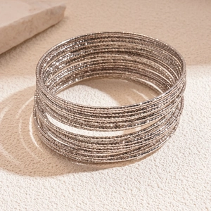 Dettaglio di bracciali multistrato in metallo argento con finitura superficiale testurizzata