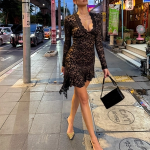 Detail of sexy black lace mini dress with deep V-neck and ruffles in urban setting