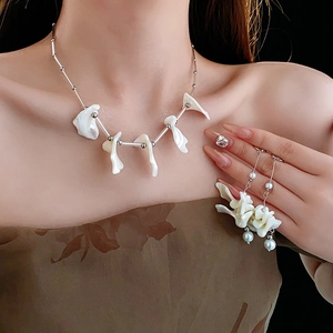 Dettaglio di orecchini con nappa in madreperla e collana su modella con luce soffusa