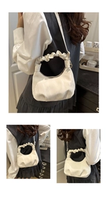 Detail of white pleated cloud bag with glossy finish and unique gathered top handle