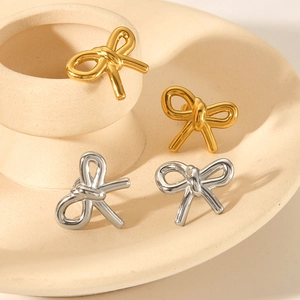 Bow knot earrings in gold and silver finish on a ceramic plate, elegant jewelry set