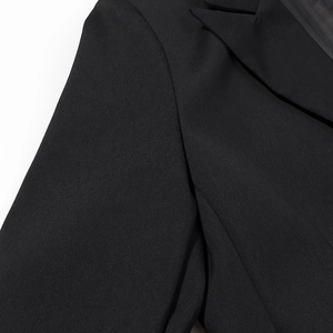 Detail shot of black twill suit jacket showing notched lapel and fabric texture