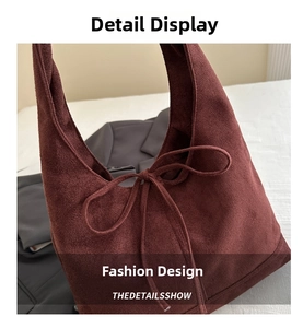 Close-up of burgundy suede tote bag featuring a decorative bow tie and soft texture