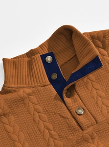 Macro shot of brown cable-knit polo shirt with contrast navy collar and metallic buttons