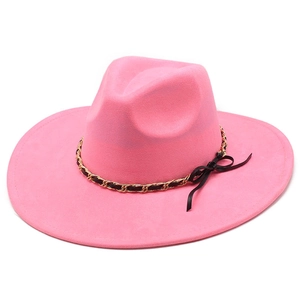 Detail of pink fedora featuring golden chain trim and a small black ribbon bow decoration