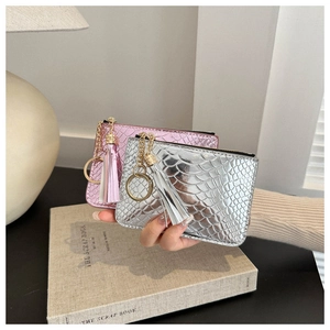 Detailed view of pink and silver faux crocodile texture coin purses with gold hardware tassels