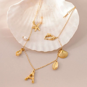 Detail view of gold starfish and shell necklace with pearls nestled in a scallop shell