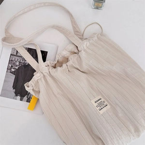 Détail macro de la texture plissée d'un sac cabas beige avec bandoulières et étiquette