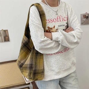 Detail of a large yellow plaid wool shoulder bag styled with a retro college outfit