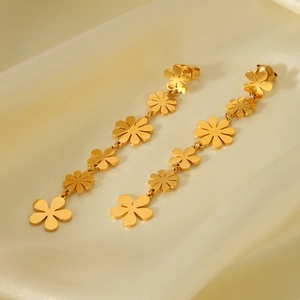 Detail of 18k gold plated stainless steel daisy tassel earrings on yellow silk backdrop
