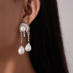Close-up of geometric pearl drop earrings with sparkling rhinestones on model's ear