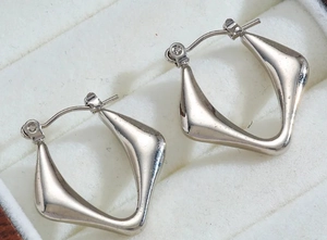 Close-up of irregular silver geometric earrings in a white jewelry display box