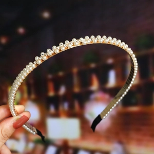 Detailed close-up of golden headband with elegant white pearls and tiny crystals