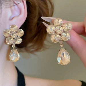 Detail showing crystal flower and teardrop earrings with champagne gold finish