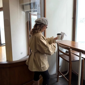 Women's chic beige short coat with belted waist and lapel collar in minimalist style