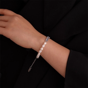 Detailed view of pearl and rectangular zircon bracelet on a model's wrist