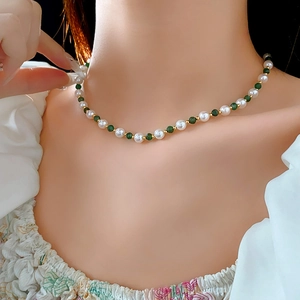 Detail of beaded necklace with white pearls, green gemstones, and gold spacer beads