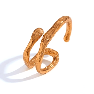 Minimalist snake-shaped gold ring with irregular hammered texture on white background
