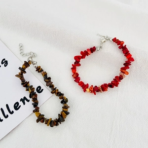 Detail of tiger eye and red stone bracelets with adjustable lobster clasp on white fabric