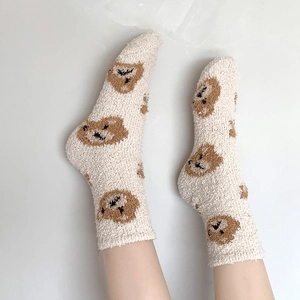 Close-up of thick coral fleece socks with cute brown bear patterns on white fabric