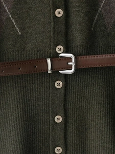 Détail du cardigan en maille losange vert olive avec ceinture cuir et boucle argent