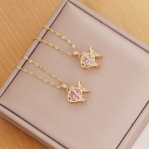 Detail of 18K gold fish pendant necklace with sparkling zircon on jewelry box