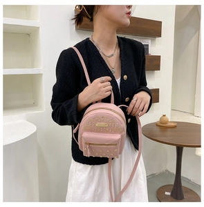Close-up of pink mini backpack with gold studs on a model in a stylish indoor setting
