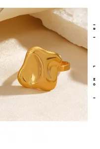Detail of a golden irregular wavy textured square ring on white mineral stone