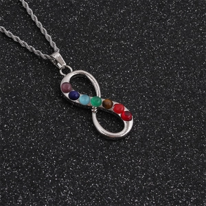 Detail of silver infinity chakra pendant with seven colorful gemstones on a rope chain