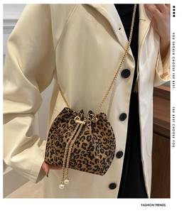 Detail of leopard print bucket bag with gold chain strap and pearl drawstring accents