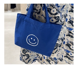 Close-up of royal blue canvas tote bag featuring a white smiley face and thick fabric