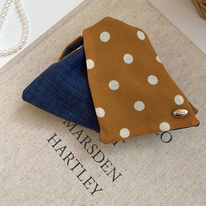 Close-up of yellow polka dot fabric and blue denim texture with engraved metal love tag