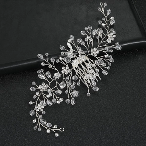 Silver bridal hair comb with crystal flowers and pearls on a textured black background