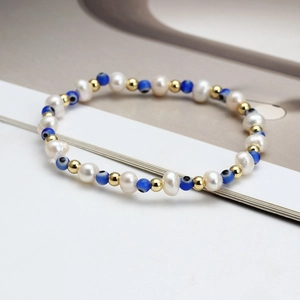 Detailed close-up of beaded bracelet with white pearls and blue evil eye charms