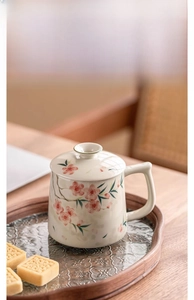 Detail of hand-painted peach blossom ceramic mug with lid on a vintage wooden tray