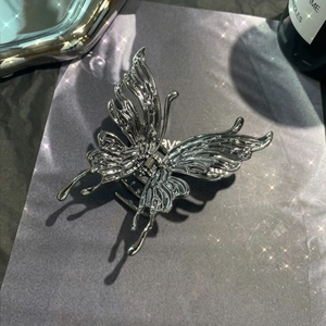 Detailed view of a silver butterfly hair claw clip with a glossy liquid metal texture finish