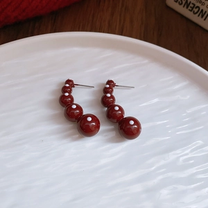 Detailed close-up of red polka dot acrylic earrings on a ripple white ceramic tray