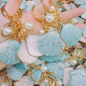 Detail of light blue shell keychain with rhinestones, pearl, and gold lobster clasp