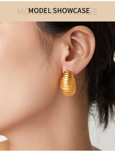 Detailed view of a gold C-shaped earring with spiral texture worn by a female model