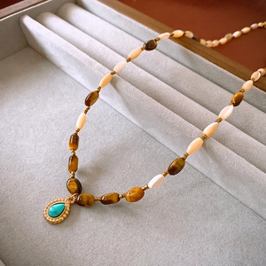 Detail of beaded necklace with tiger eye stones and vintage gold turquoise pendant